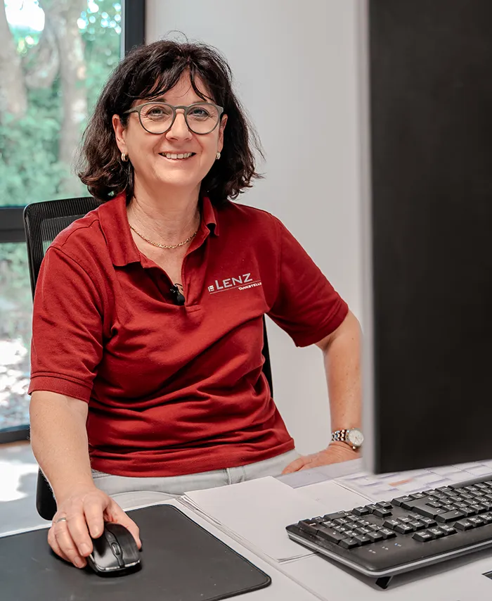 Pellethändler Weinheim - Kundenberaterin Frau Teichtinger an ihrem Arbeitsplatz vor ihrem Computer, sie trägt ein rotes Poloshirt mit dem Logo der Firma Lenz Energie